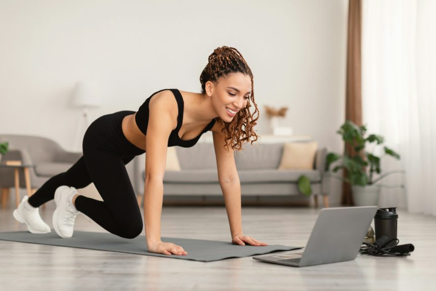 Female Near Laptop Doing Plank Exercise Training At Home